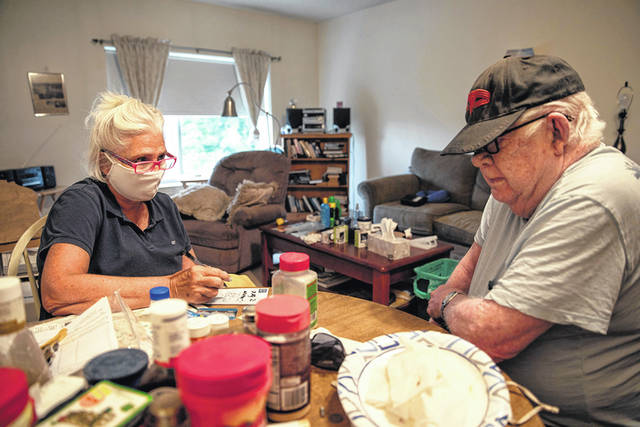 Kathleen McAuliffe, a home care worker for Catholic Charities in a Portland, Maine, suburb, helps client John Gardner with his weekly chores. McAuliffe shops for Gardner’s groceries, cleans his home and runs errands for him during her weekly visit. 