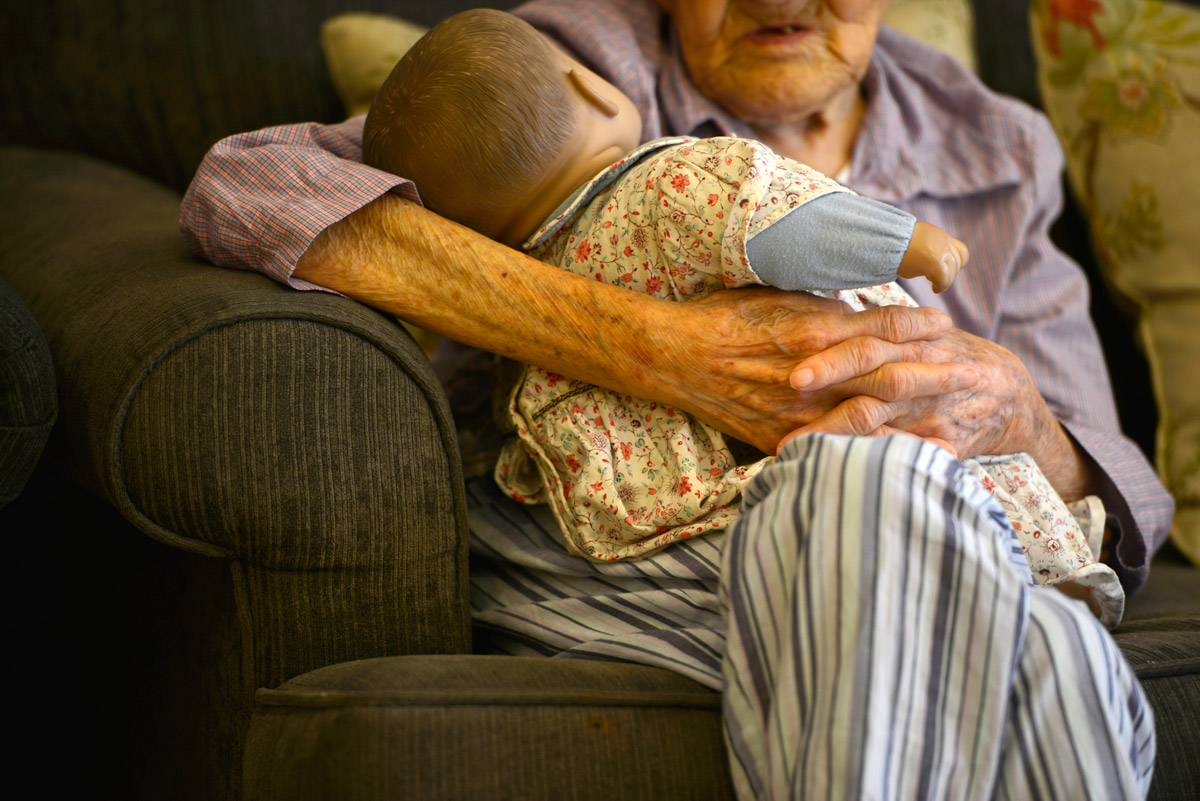 An elderly woman holds a doll at a nursing home for people diagnosed with Alzheimer’s disease, Beijing, 2015. Feng Li/VCG